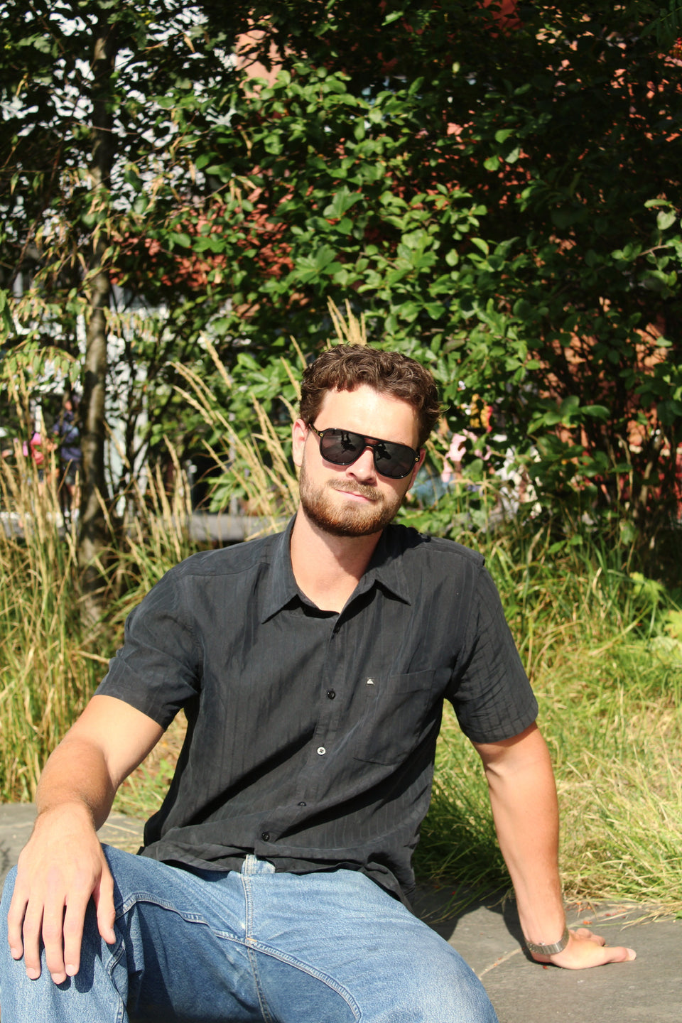 Mann mit Luca Costa Black, sitzend im hohen Gras an der Munch brygge in Oslo